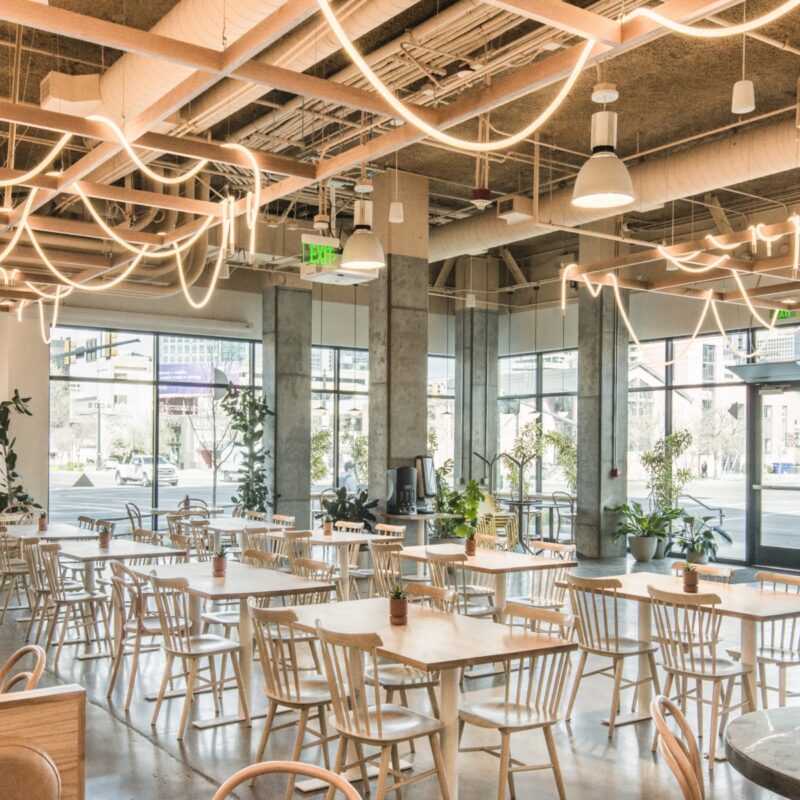 Internal image of The Eatery featuring table and chairs with large open windows and greenery